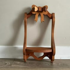 a wooden chair sitting on top of a hard wood floor next to a white wall