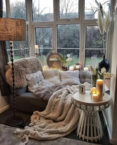 a living room filled with lots of furniture next to a large window covered in blankets