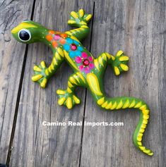 a green and yellow lizard figurine sitting on top of a wooden table