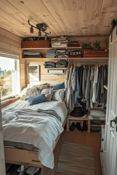 a small bedroom with a bed, closet and clothes hanging on the wall next to it