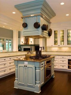 a blue kitchen island with pots and pans hanging from it's ceiling over the stove