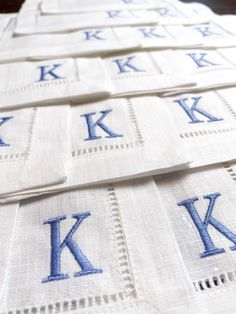 the monogrammed napkins are laid out on top of each other with blue letters