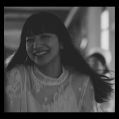 a woman with long hair laughing and wearing a white shirt in front of other people