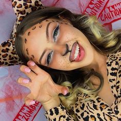 a woman with painted on her face and leopard print shirt, posing for the camera