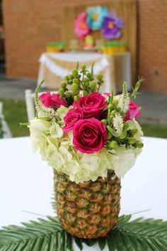 a pineapple vase filled with flowers on top of a white tablecloth covered table