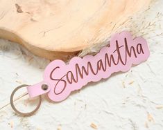 a pink keychain with the word savannah on it sitting next to a piece of wood