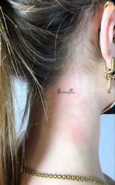 a woman's neck with the word love tattooed on her left side behind her ear