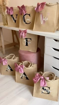 several bags with pink bows on them are sitting in front of a white table and drawers