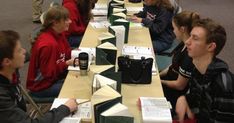 a group of people sitting at long tables with books