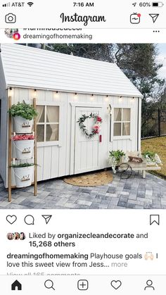 a small white shed with potted plants and wreaths on the front door area