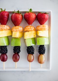 fruit kabobs are arranged on a white plate