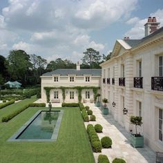 a large white house with a pool in the middle of it's garden area