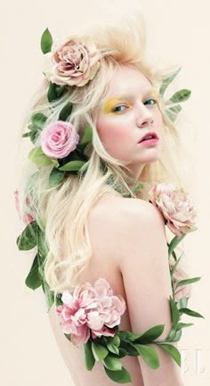 a woman with long blonde hair and flowers on her head is posing for the camera