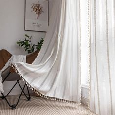 a white curtain with tassels hanging from it's side in front of a window