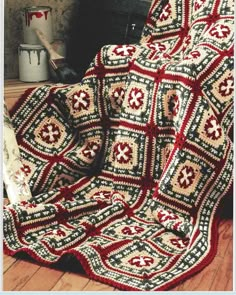 a crocheted afghan sits on the floor in front of a fireplace with a blanket draped over it