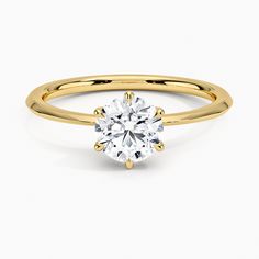 a yellow gold engagement ring with a round cut diamond in the center, on a white background