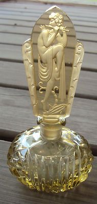 an old glass bottle with a gold decoration on the top and bottom, sitting on a wooden table