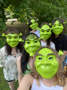 several people with green masks on their faces and one woman has her face painted to look like an alien