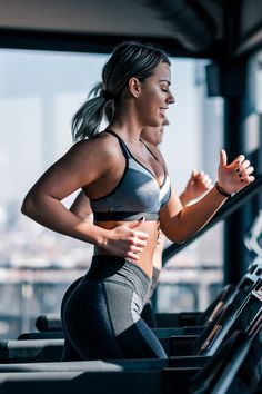 a woman running on a treadmill in the gym with her hands behind her back