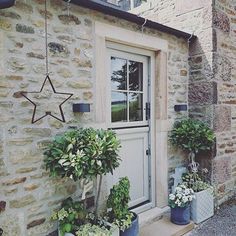 potted plants line the side of an old stone building with a star hanging from it's door