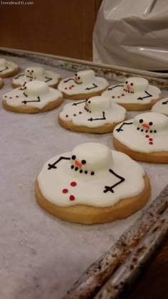 cookies decorated with white frosting and black dots are lined up on a baking sheet