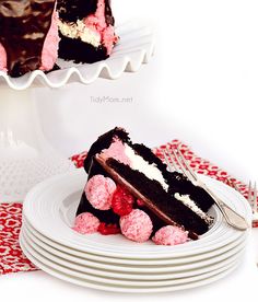 two pieces of chocolate cake with raspberries on top and one slice missing from it