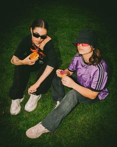 Two young brunette girls are sitting on grass eating donuts. They’re both wearing sunglasses and streetwear outfits. Their attitude is cool and laidback. Eating A Donut Pose, Streetwear Flash Photography, Street Clothing Photoshoot, Group Photoshoot Ideas Outdoor, Daylight Flash Photography, Urban Streetwear Photoshoot, Group Shoot Ideas, Dunkin Photoshoot, Streetwear Photoshoot Ideas Outdoor