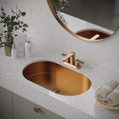 a bathroom sink with gold faucet and marble counter top next to a round mirror