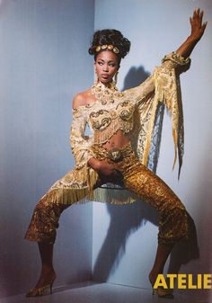 a woman in an elaborate outfit poses for a magazine cover photo with her hands on her hips