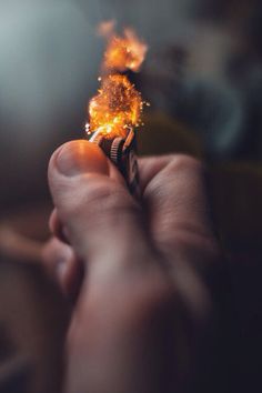 a person holding a lighter in their hand with flames coming out of the top of it