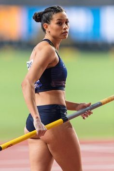 a woman holding a baseball bat on top of a field