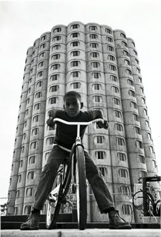 a boy on a bicycle in front of a tall building