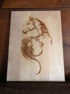 a wooden cutting board with a horse on it's face in the shape of a dragon