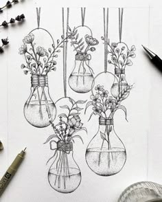 three vases with flowers in them are hanging from the ceiling next to some pens and markers