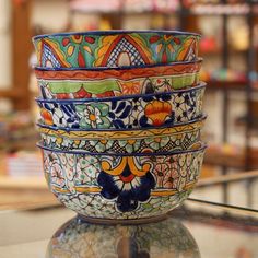 a stack of colorful bowls sitting on top of a glass table