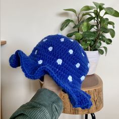 a crocheted blue hat sitting on top of a wooden table next to a potted plant