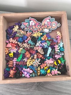 a wooden box filled with lots of different colored little bugs on top of a table