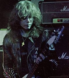 a man with long hair playing an electric guitar