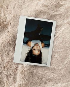 a polaroid photo of a woman laying on top of a white fluffy blanket with her eyes closed