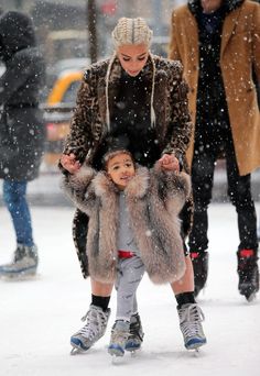 a woman and child are skating in the snow