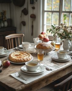 a wooden table topped with plates and cups filled with food next to an apple pie