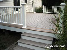 a deck with white railings and steps leading up to the front door is shown