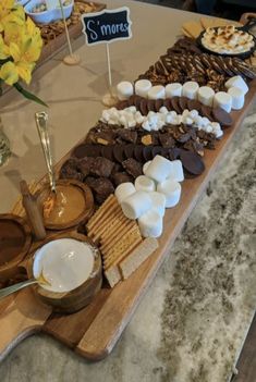 a wooden tray topped with lots of different types of desserts and marshmallows