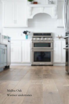 an image of a kitchen setting with wood flooring and stainless steel appliances in it