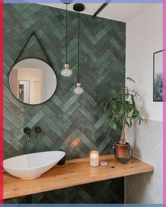 a bathroom with a mirror, sink and potted plant on the counter in front of it