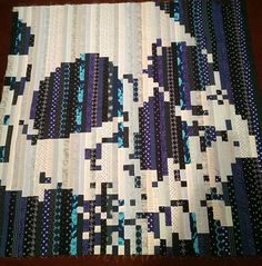 a close up of a quilt on a table top with blue and white strips in the center