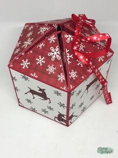 an origami box with red ribbon and snowflakes on it