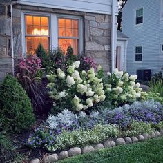 a house with flowers in front of it and a window on the side of the house