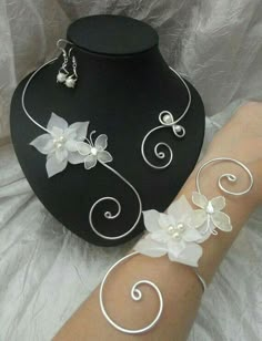 a woman's arm with white flowers on it next to a black mannequin