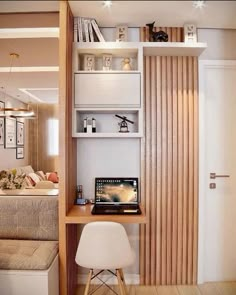 a laptop computer sitting on top of a wooden desk next to a white chair and bookshelf